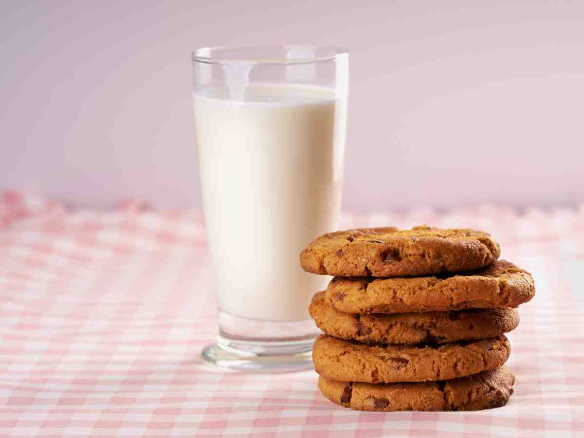 un bicchiere di latte e 5 biscotti su un tavolo