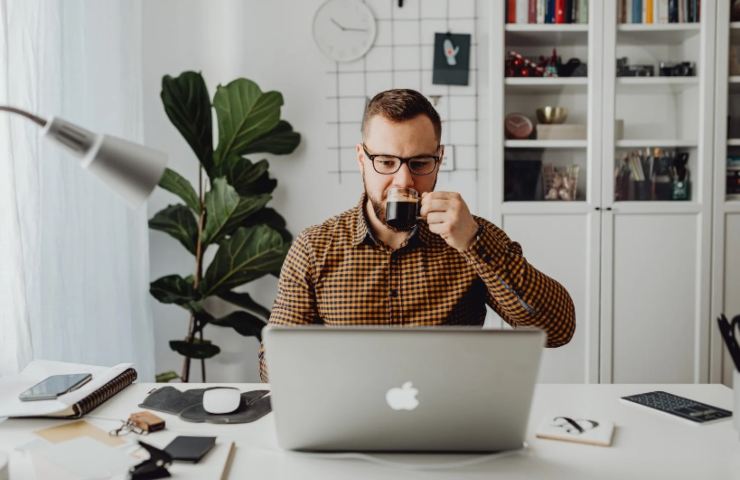 Uomo beve il caffè davanti al pc 