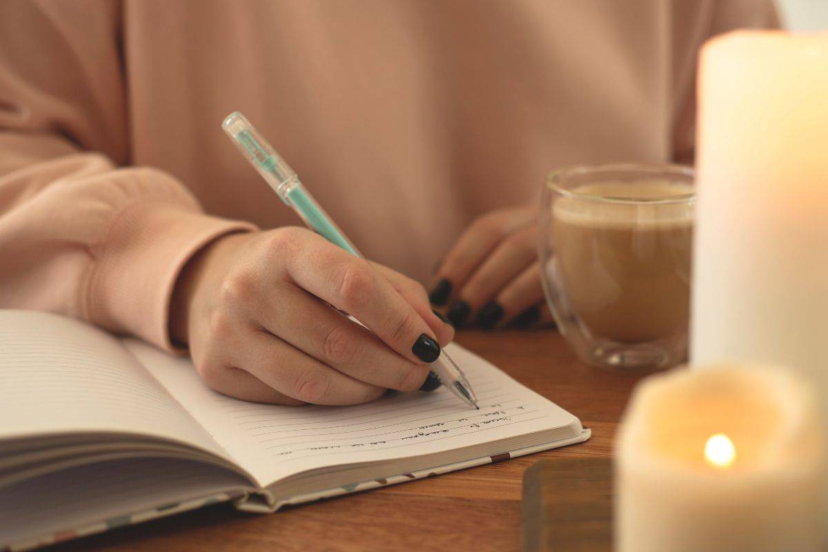 ragazza che scrive su un quaderno a lume di candela