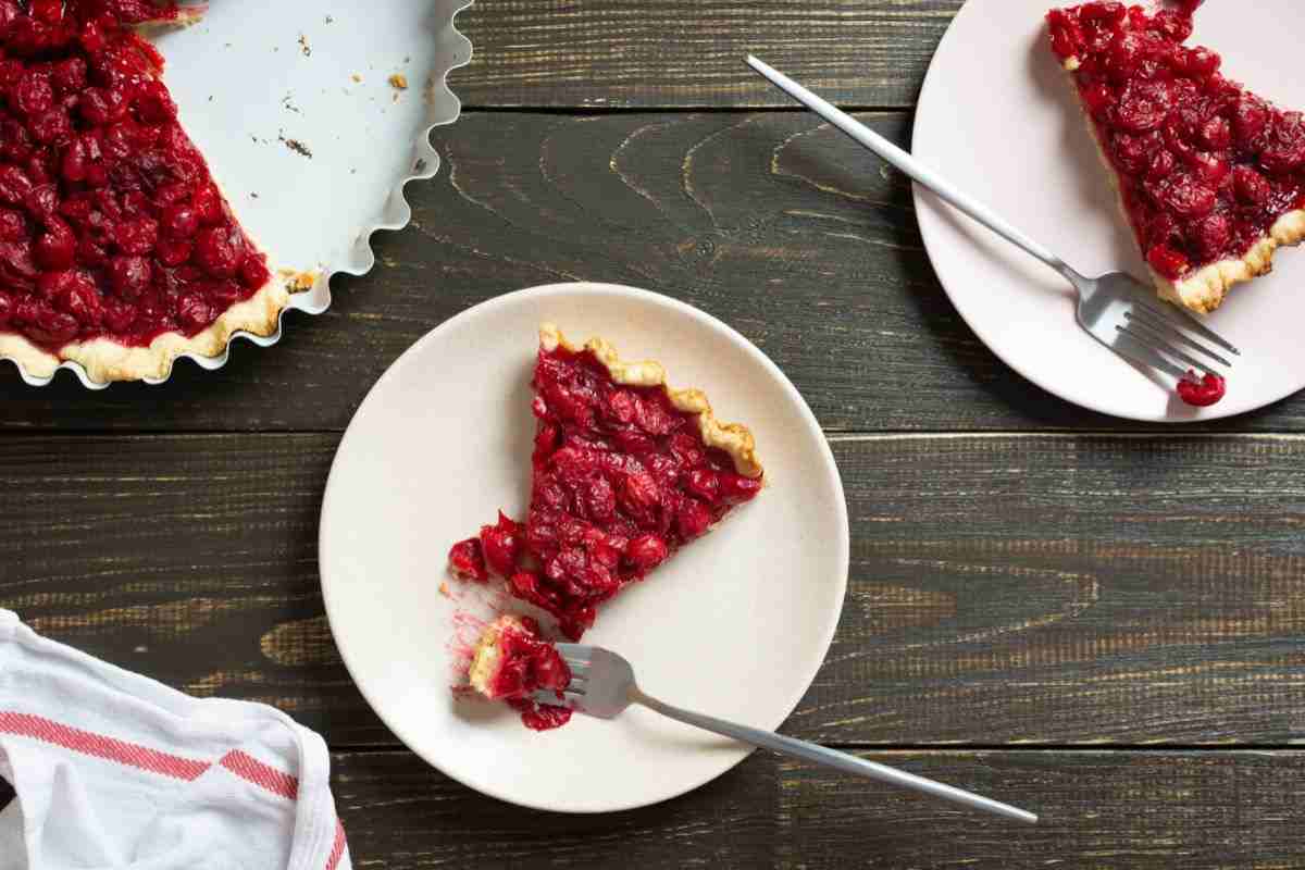 fette di crostata ai frutti di bosco in piatti bianchi su tavolo di legno scuro